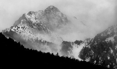 Black and white winter landscape of snow covered mountains and sky with clouds