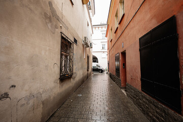 Narrow Tarnow alley in Poland with wet cobblestones, graffiti walls, and shuttered buildings