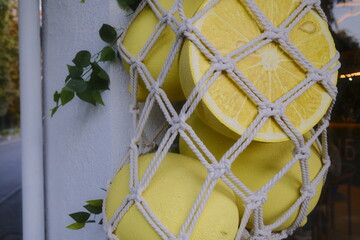 Yellow fruit hangs in a knotted bag, decorating the side of a building.