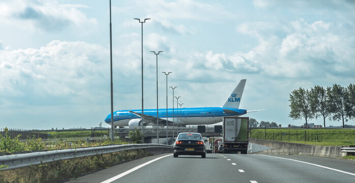 Hague, Netherlands - Aug 26, 2024: A KLM airplane crossing above a busy Dutch highway with cars passing below under cloudy skies.