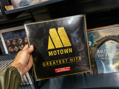 Munich, Germany - Aug 9, 2025: Vinyl record of Motown Greatest Hits held in hand inside music shop with shelves of other records visible in background.