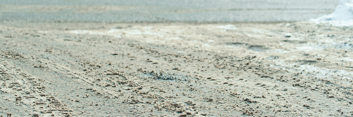 Tire tracks on sandy road surface in dry outdoor environment.