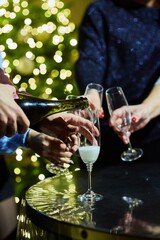 Hands on the background of a Christmas or New Year's tree with glasses of champagne