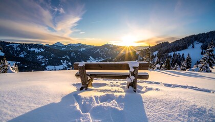 A snowy landscape features a wooden bench overlooking mountains, bathed in the warm glow of a sunset. Sunbeams burst through the sky