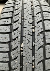 Close-up view of a tire tread with embedded small stones, displaying intricate patterns and texture.