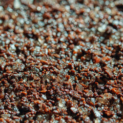 Close-up view of coarse coffee grounds with shimmering crystals in sunlight.