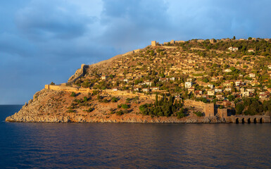 Golden sunset light illuminates Alanya Castle and the ancient fortress walls above the Mediterranean Sea in Alanya Turkey, showcasing historic architecture and scenic coastal beauty