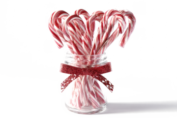 Festive candy canes in a glass jar with a red ribbon holiday treat for Christmas and winter celebrations isolated on white