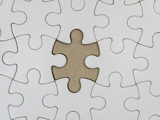 Incomplete white jigsaw puzzle with a missing final piece