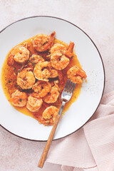 Savory shrimp dish served in a white plate with flavorful sauce and herbs