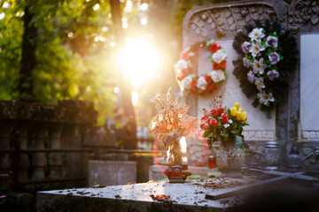 Cemetery grave with flowers and wreaths illuminated by warm sunset light &mdash; symbol of remembrance and peace