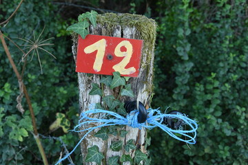 blue rope and a yellow pitch number on a red sign on a standing wooden sleeper on a camping site