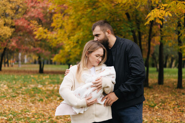 Young caucasian parents with newborn baby in autumn park