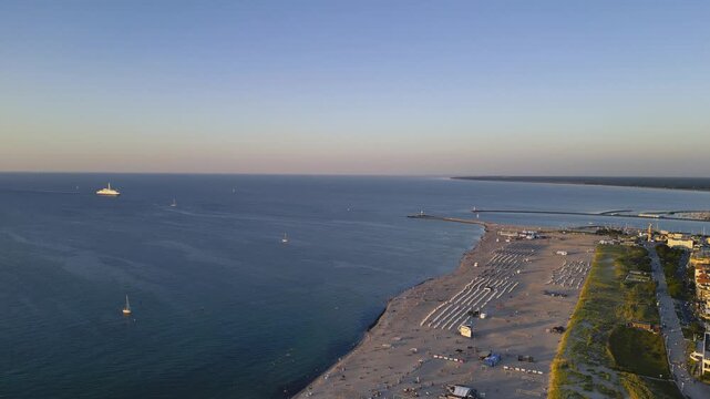 Rostock, Germany – August 17, 2024: Aerial view of Warnemünde Beach on the Baltic Sea at sunset. Hotels, beach chairs, and promenade along the scenic coastline.