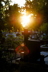 Cemetery cross illuminated by bright sunset light and lens flare, faith and hope concept
