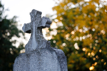 Dramatic sunlight shining through a cross in a peaceful cemetery, symbolizing eternal faith and light.