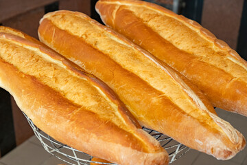 Freshly baked baguettes displayed on a wire basket in a bakery during the morning hours