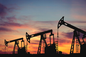 Silhouette of oil pumps against the backdrop of sunset. Illustration of oil extraction from oil fields. Concept of global oil and gas production and energy resources.