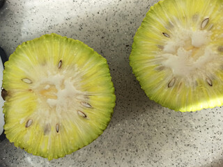 cutting Maclura Pomifera fruit on halves on desk. close up