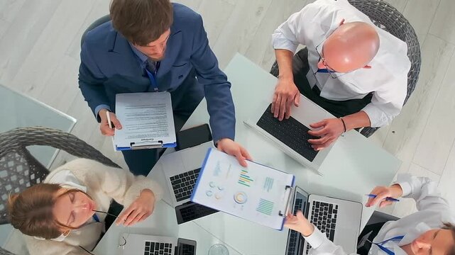 analysts review and discuss charts, analysts collaboratively analyze charts and discuss data insights thoroughly, team collectively reviews detailed charts and discusses key performance metrics