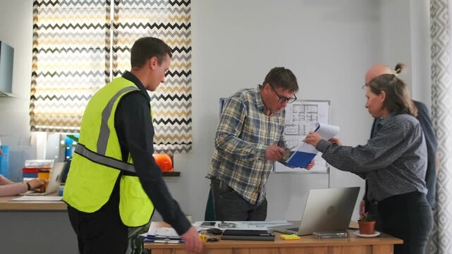project manager leads team through plans at desk, professional woman presents documents to construction crew and architects, organized meeting with clear action items and collaborative decision making