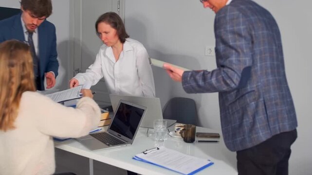 caucasian team collaborates efficiently, team of caucasian individuals reviewing and signing documents at table, caucasian team members rapidly exchanging and reviewing documents with sense of urgency
