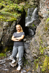 A female tourist on the background of the Altai waterfall in the mountains. Traveler's Walking tour