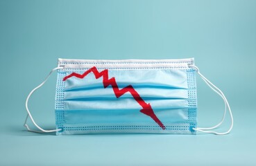 Medical mask shows falling graph in red color. It is symbol of economic recession, financial collapse, crisis and market decline. Blue face mask for virus protection, flu. Pandemic concept. Debt.