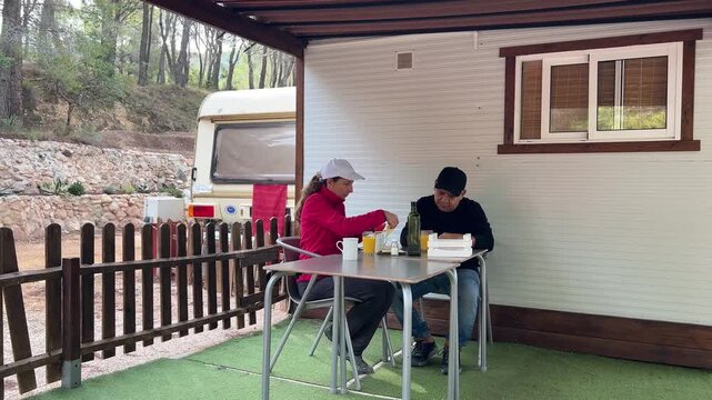 Pareja desayunando frente a su caravana 4K