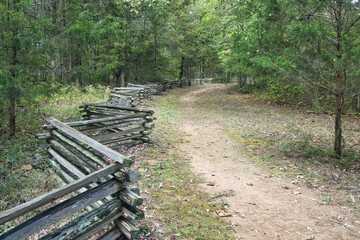 Autumn landscape of a nature trail beside a zigzag split rail fence in a lush forest along the Natchez Trace Parkway in Tennessee.