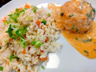 Delicious Rice With Colorful Vegetables and Savory Meatballs on a White Plate