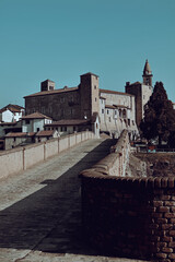 Monastero Bormida in Piedmont, Italy. An ancient Italian town with a historic stone bridge over the river surrounded by spring greenery. A peaceful and scenic landscape rich in heritage.