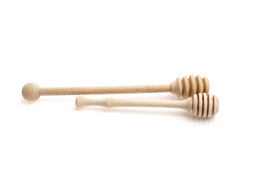 Two wooden honey dippers, one with a round end and the other with a spiral design, placed on a white background, showcasing craftsmanship and natural materials for culinary use