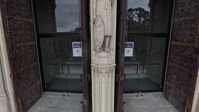 Detailed stone sculptures at the entrance of Washington National Cathedral, gothic portal view. drone rises.
