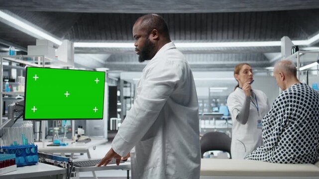 Green screen next to black medic studying data for drug testing in lab, evaluating dosage and potential side effects. Checking chemical reactions and safety to support science breakthrough. Camera A.