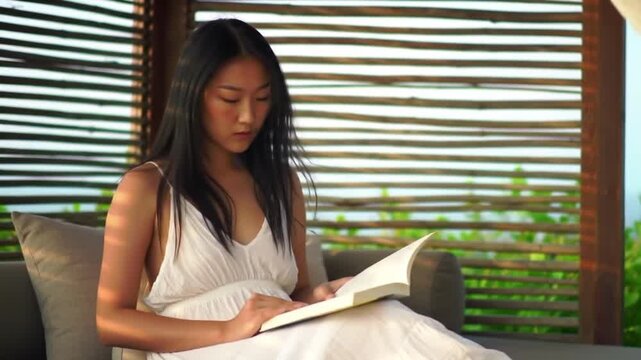 Woman reading book in outdoor lounge area with slatted backdrop