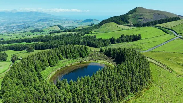 Green lush Sao Miguel volcanic landscape and round Pau Pique lake in caldera volcano, Azores, Aerial view