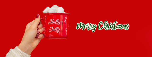 A hand holding a red Christmas cup with the text “Merry Christmas”