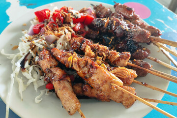 A plate of food with meat and vegetables on it, satay kambing