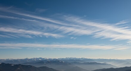 Fototapeta premium Panoramic view of mountain range under a bright blue sky with wispy clouds