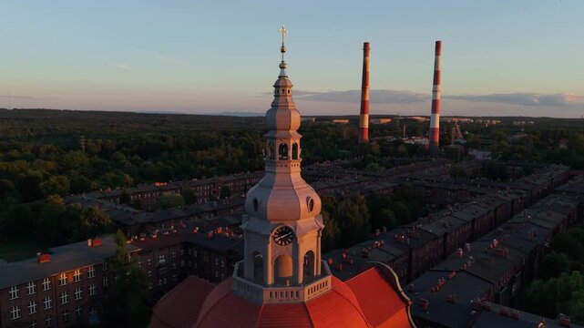 Aerial drone footage of Nikiszowiec district in Katowice, Poland, during a beautiful sunset. Historic red brick buildings glowing in golden light, showcasing unique urban architecture.