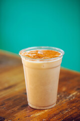A plastic cup filled to the brim with Mexican horchata topped with ground cinnamon at a Mexican modern food restaurant