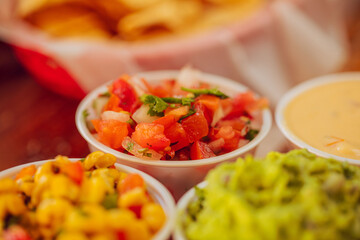 A closeup of various salsas at a mexican restaurant including tomato corn and guacamole