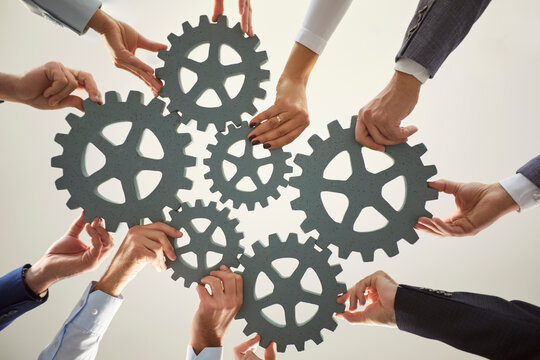 Bottom view of hands holding interlocking gear wheels, symbolizing teamwork, collaboration and connection. Business concept of cooperation, partnership and joint efforts for achieving shared goals.
