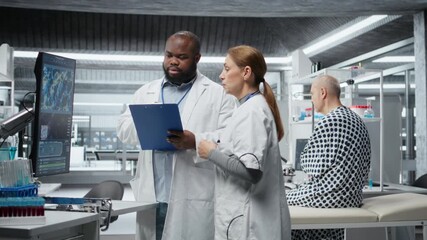 Two researchers testing a patient during a drug trial and recording side effects, monitoring dosage and studying allergic reactions. Biotechnology and clinical research. Camera A.