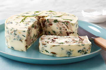 Creamy terrine round wedge teal plate herb garnish sliced portion cheese texture savory spread cold appetizer gourmet snack rustic style delightfully