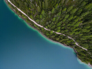 Tranquil aerial view of idyllic Lago di Braies lake shore. Calm, turquoise water, forest and a footpath. Pragser Wildsee, Dolomites, Italy