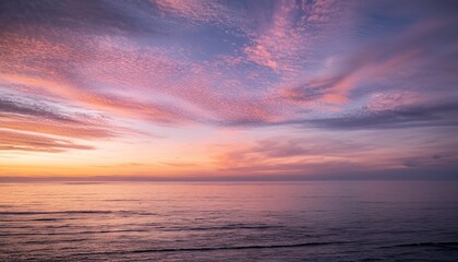 Obraz premium Evening sky with pink cirrus clouds over calm ocean water at sunset 
