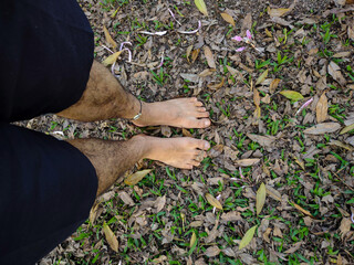 A unique view of bare feet on a ground covered in dry and green leaves, capturing the connection with nature and the freedom of the senses. Natural light highlights the texture of the leaves and skin.