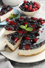 Taking piece of delicious cheesecake with berries at grey table, closeup